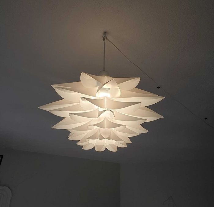 A reviewer's photo showing the lotus pendant light hanging from the ceiling, adding a touch of elegance to the room.