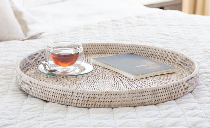 A circular rattan tray gracefully placed on a bed.