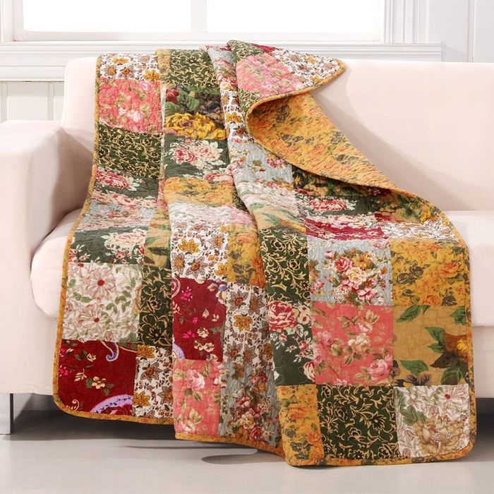 A floral patchwork quilt draped over a sofa.