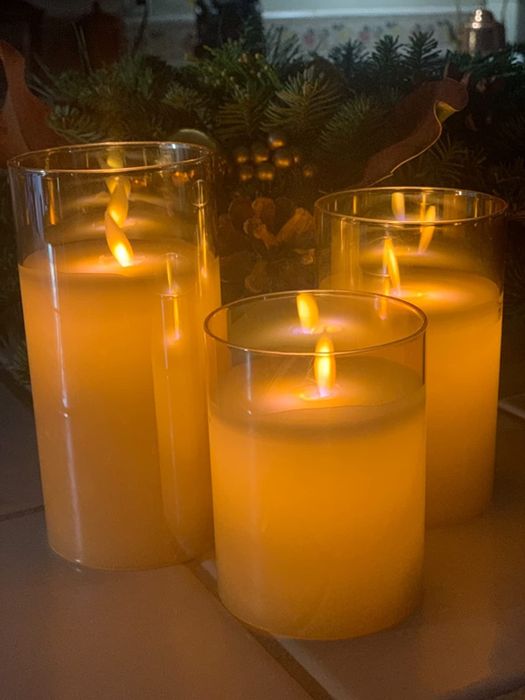 A trio of flameless candles nestled in clear glass cylinders.