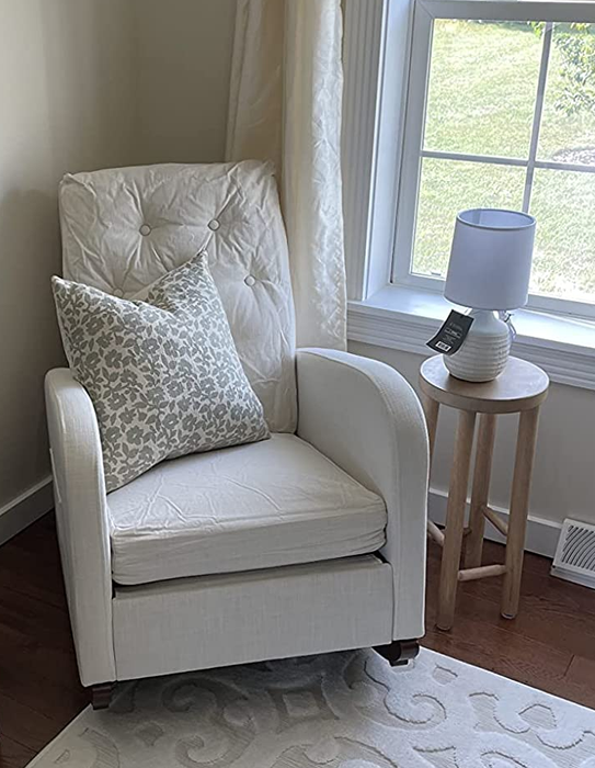 Reviewer image of a tufted white upholstered rocking chair, complemented by a floral white and gray throw pillow