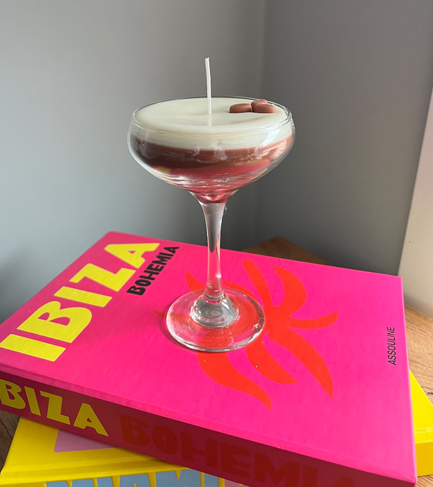 A candle designed to look like an espresso martini in a stemmed glass.
