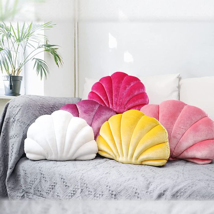 Pink, white, and yellow seashell-shaped pillows on a gray couch