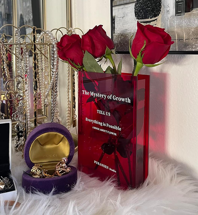 Another reviewer's red book-shaped vase holding vibrant red roses, placed on a jewelry-adorned vanity alongside a luxury watch box and a stunning bracelet display