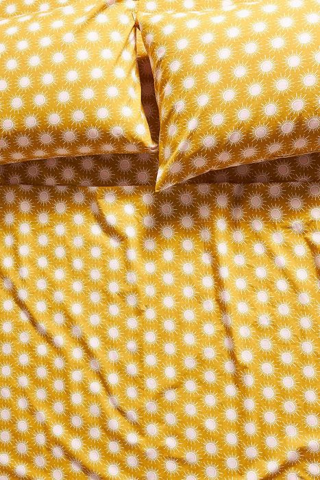 The yellow sunburst patterned sheet set displayed on a bed