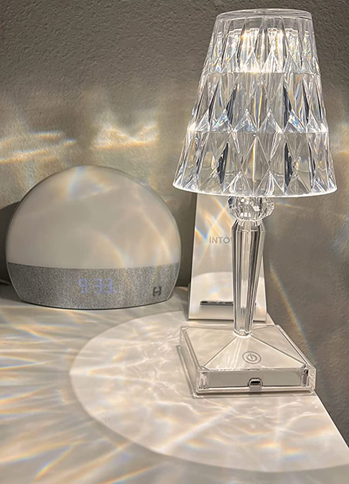 A small crystal table lamp turned on, casting shimmering prisms of light across the table.
