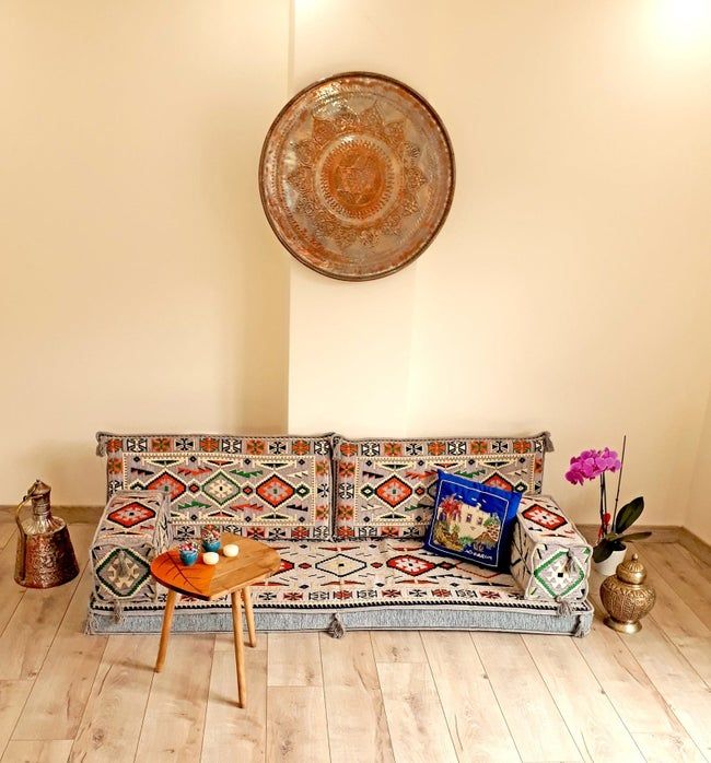 Turkish-style floor sofa placed on a wooden floor, beside a table.