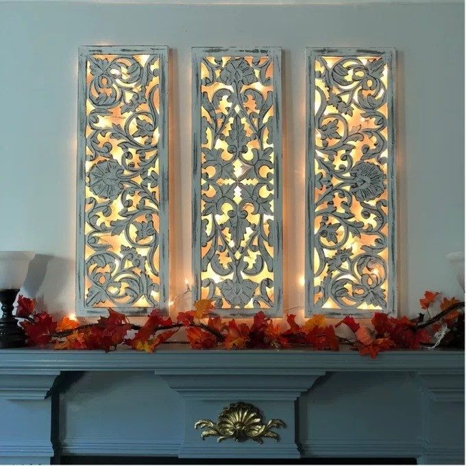 the three-panel set with lights glowing behind and surrounded by leaves