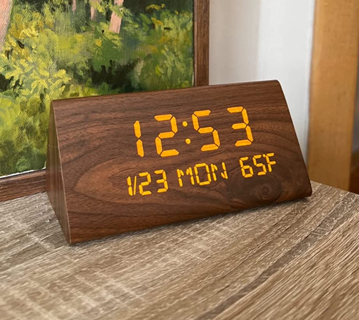 A reviewer showcases a close-up of their wooden clock on a side table