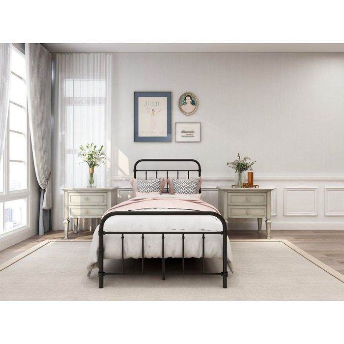 Bedroom scene featuring a metal-framed bed dressed in pink and white bedding, complemented by white nightstands, lamps, and decor pieces.