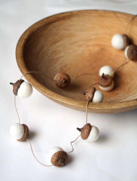 acorn caps with felted bottoms attached by thin twine, placed inside a bowl.