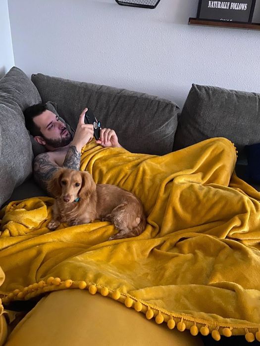 A customer shares an image of themselves and their dog cozying up under the mustard yellow blanket.