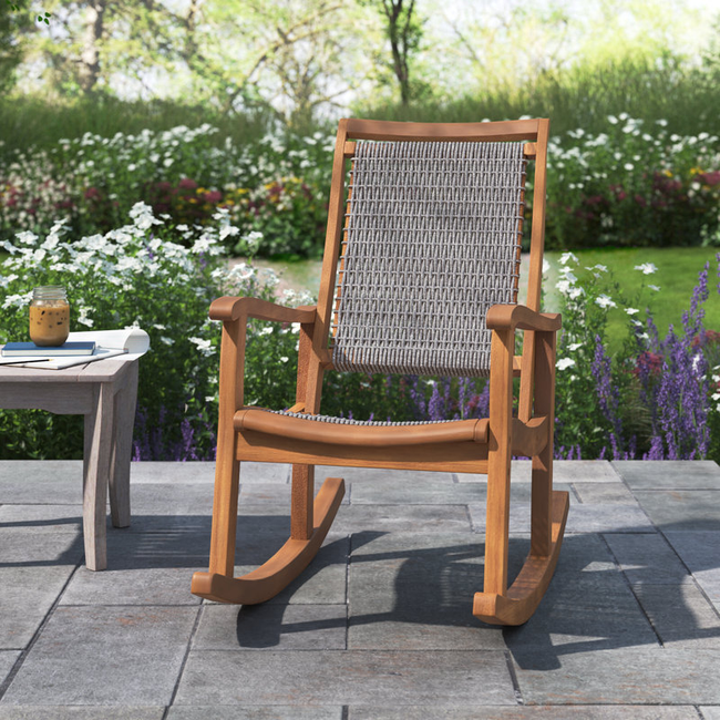 A wooden rocking chair with a woven seat, placed on a patio for a relaxing outdoor experience