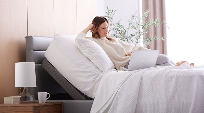 A woman lying on a mattress with an adjustable bed frame.