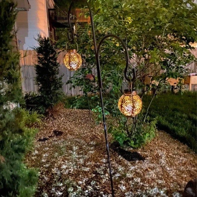 A photo shared by a reviewer showing two lanterns gracefully hanging in a yard.