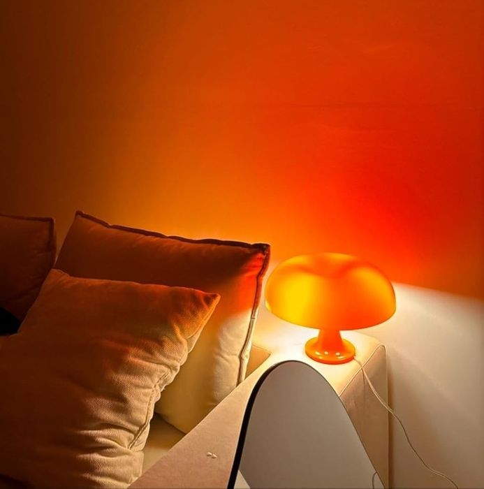 A table featuring an orange lamp and beige pillows on a sofa, creating a warm, inviting ambiance.