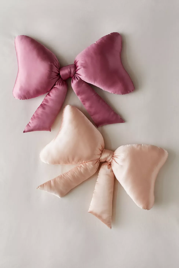An artistic arrangement of four satin knot pillows in delicate pink hues, set against a neutral backdrop.