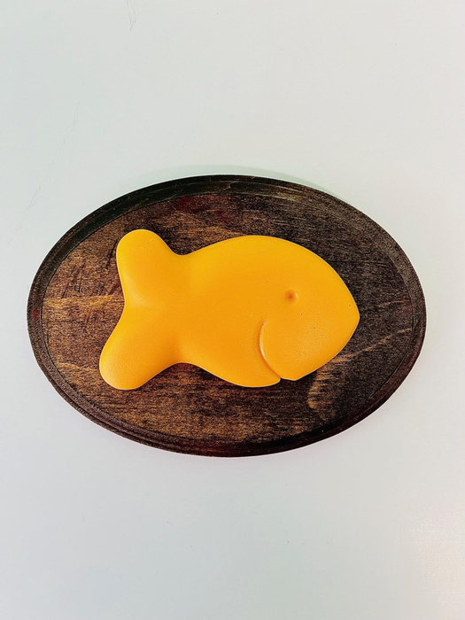 A fish-shaped loaf resting on an oval wooden cutting board.