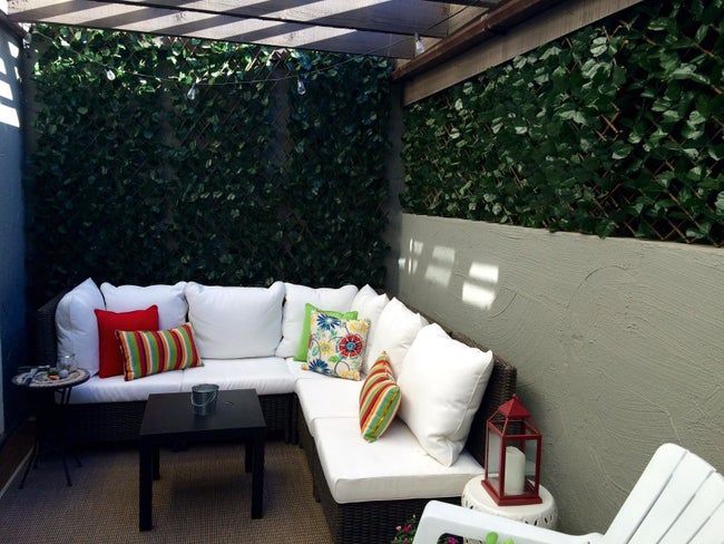 A small patio, with the artificial greenery fence screen enclosing it on two sides.