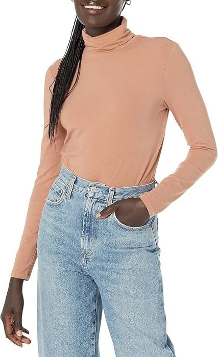 Person rocking a turtleneck with high-waisted jeans, casually posing with one hand in their pocket, ideal for a shopping article