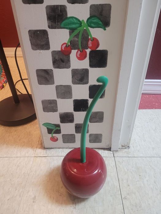A cherry-shaped toilet brush where the handle is a stem and the brush holder is the cherry itself