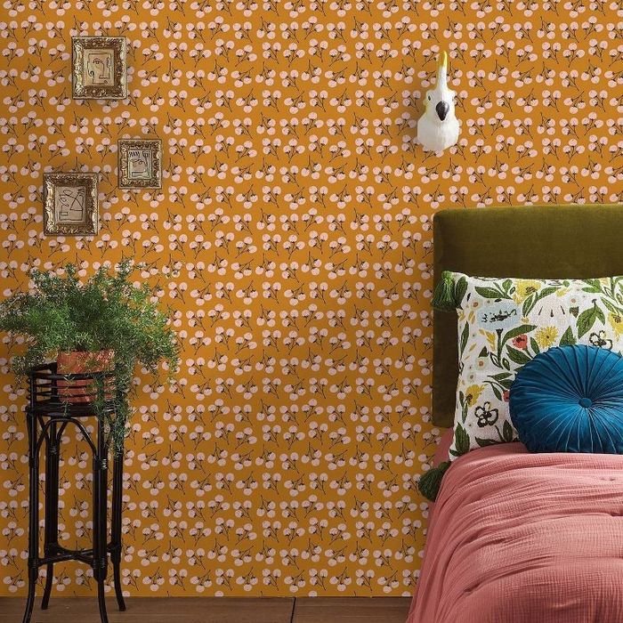 The orange wallpaper adorned with pink flowers in a bedroom.