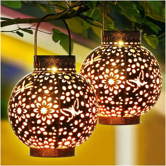 The solar lanterns with an intricate, decorative pattern hanging from a tree