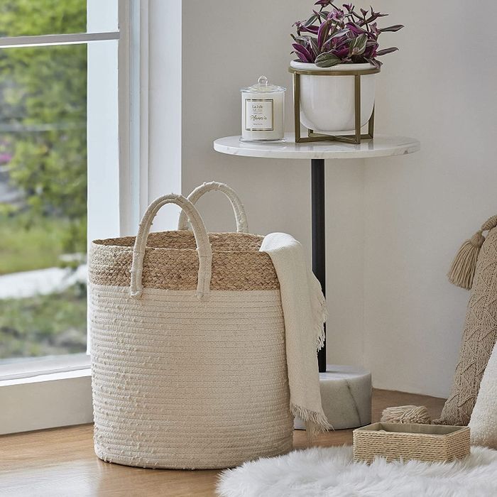 A photo of the half white and half wicker basket on the floor, filled with cozy blankets.