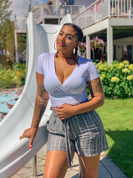 A reviewer wearing the top in white, paired with high-waisted drawstring shorts.