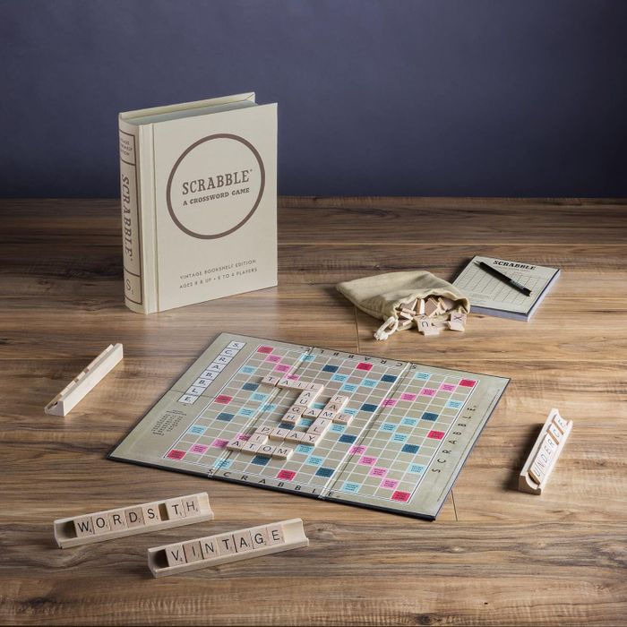 Scrabble Deluxe Edition game set spread across a table, featuring the board, tiles, racks, scorepad, and tile bag