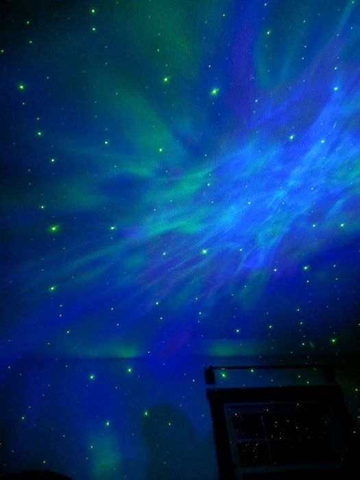 A mesmerizing blue and green nebula projected across a ceiling, creating a celestial ambiance.