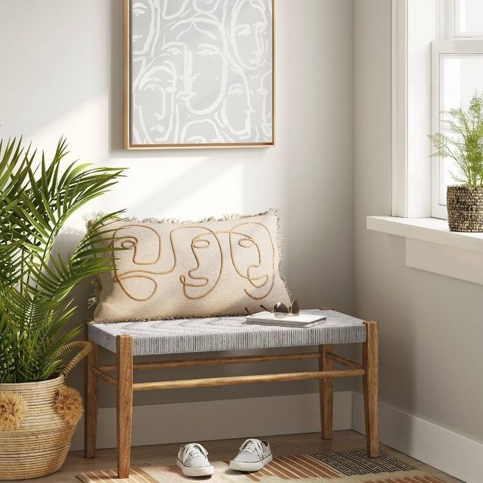 a woven bench with a pillow and a book resting on top