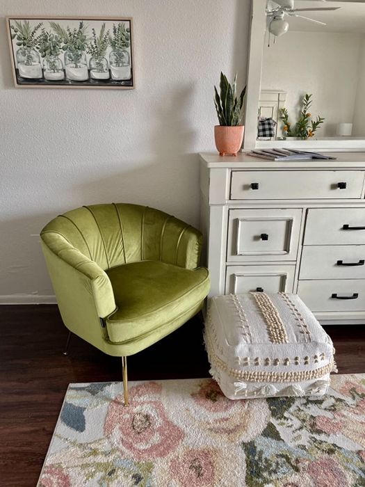 A reviewer's photo of a green chair in a cozy bedroom.