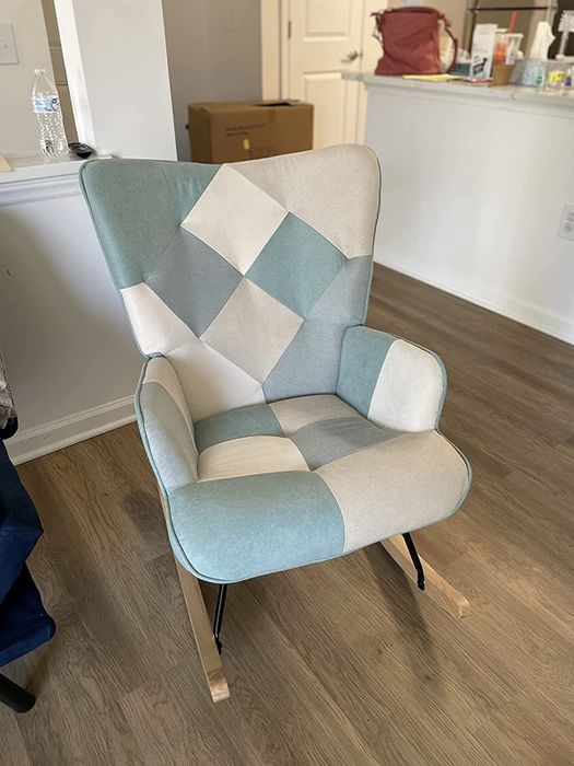 A reviewer's photo showing a blue and white patchwork rocking chair placed in the living room.