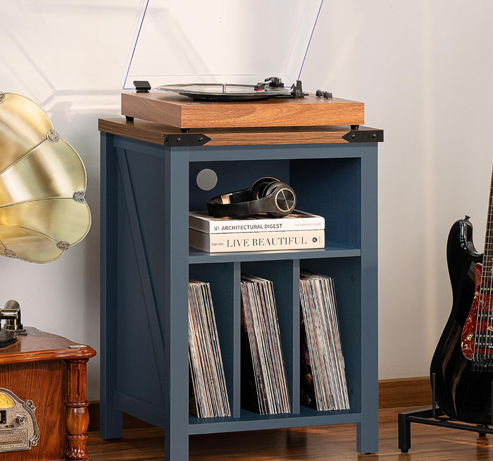 A chic blue wooden record player stand featuring a turntable on top, along with a camera, photo book, and various vinyl records in its compartments