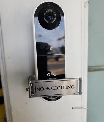 An Arlo video doorbell mounted on a wall, with its sleek design in full view.