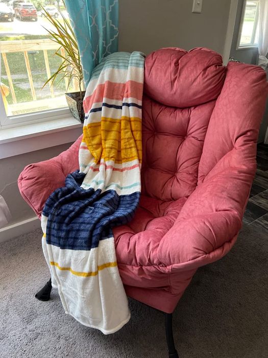 A reviewer's photo of a red lounge chair with a cozy throw blanket draped over it.