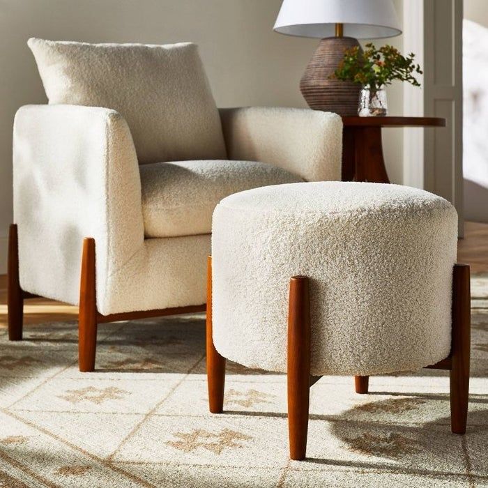 a round ottoman in cream and brown placed on a rug in a cozy living room