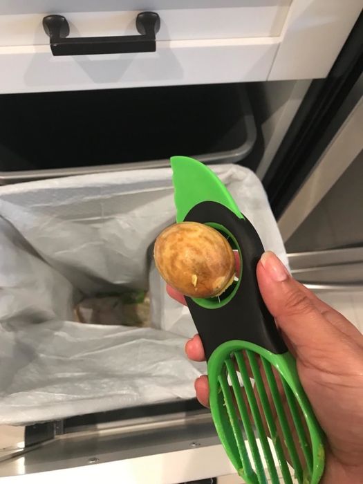 A reviewer demonstrating the pit stuck in the pit-removal blade of the avocado slicer