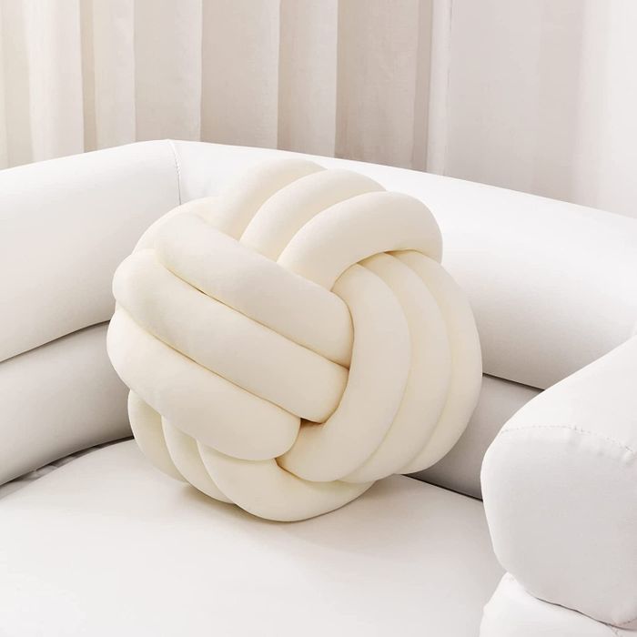 An ivory-colored knot pillow, adding a stylish accent to any space.