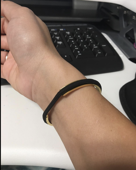 Reviewer showcasing a gold bangle with a black hair tie securely placed in its grooves