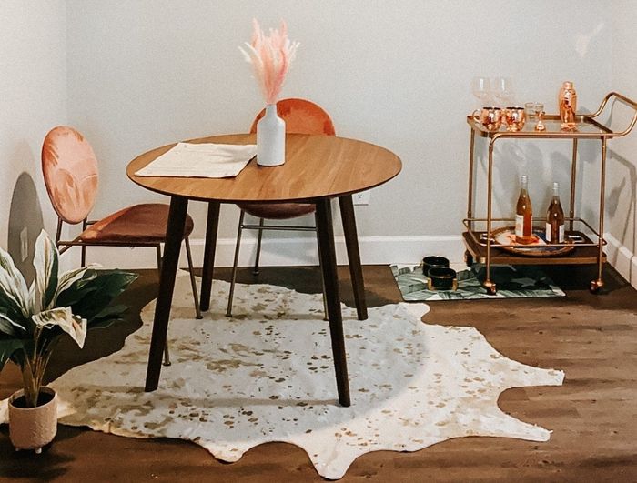 A cream-colored faux cowhide rug underneath a reviewer's dining table