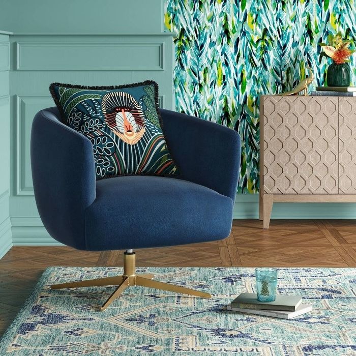 A blue and gold swivel armchair with a pillow resting on it