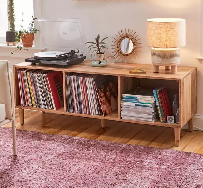 A wide, light wooden credenza featuring a record player, knick-knacks, and vinyl storage inside