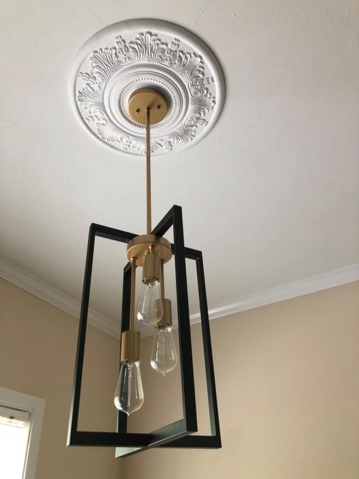 A reviewer’s picture of the white medallion installed beneath a pendant light