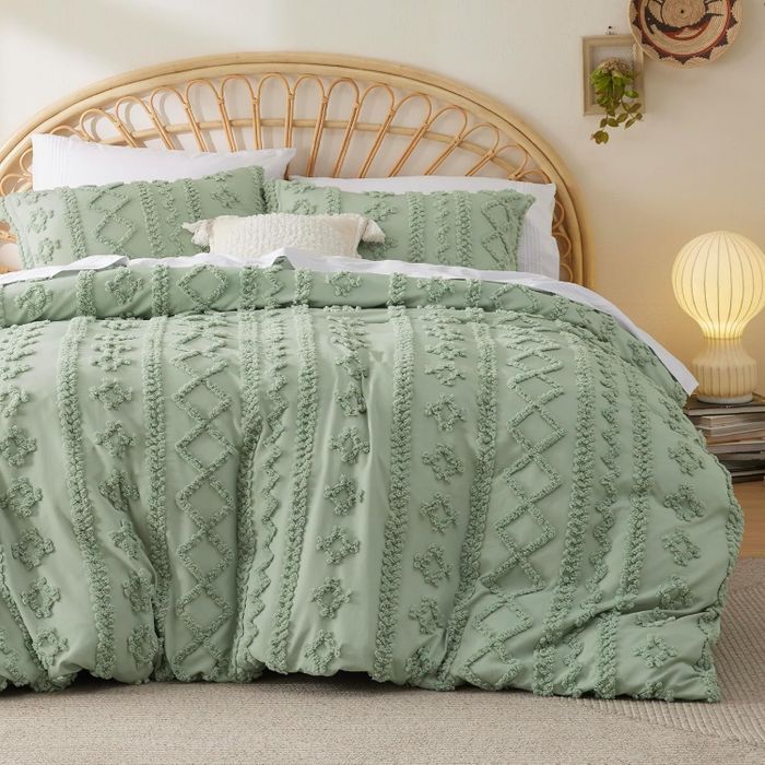 A cozy bedroom with floral-patterned bedding, soft pillows, a rattan headboard, and an elegant lamp on a nightstand, creating a serene atmosphere.
