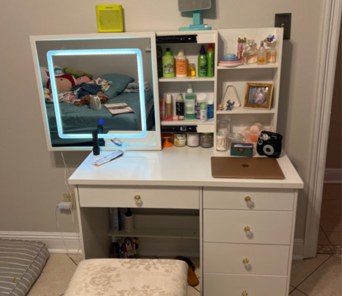 Reviewer photo of a lit-up vanity, filled with makeup and hair products