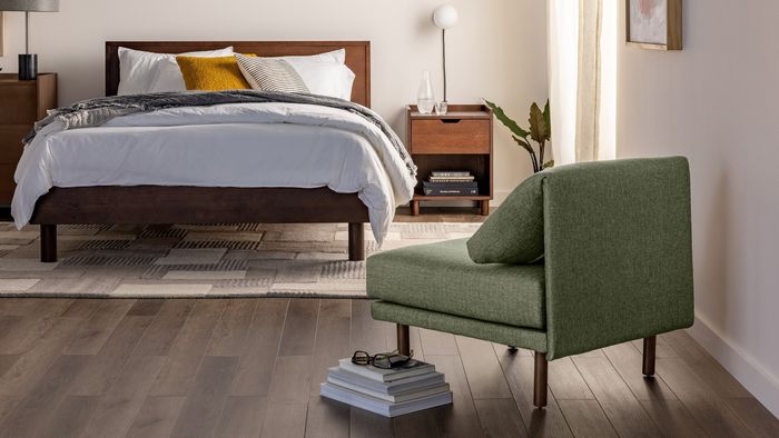 A green lounger chair placed in the corner of a bedroom.
