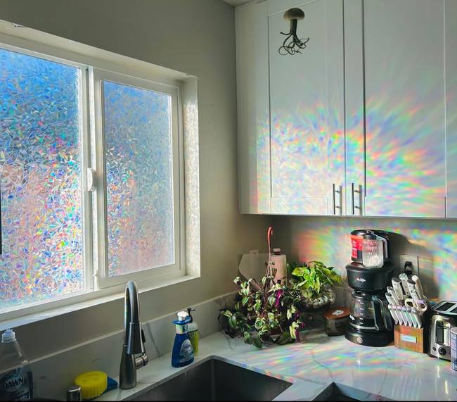 Rainbow light cascading from a prismatic window onto a kitchen cabinet.