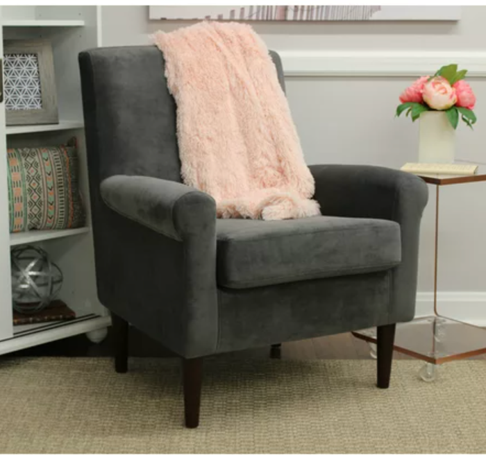 The chair in gray, adorned with a pink throw blanket draped over it.